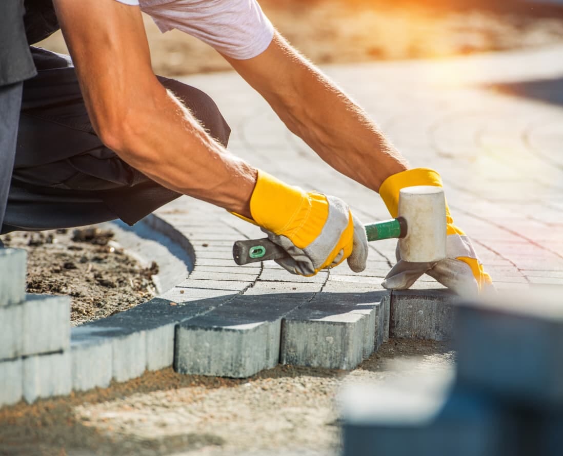 Skilled Worker Laying Paving with Precision Using a Hammer and Gloves